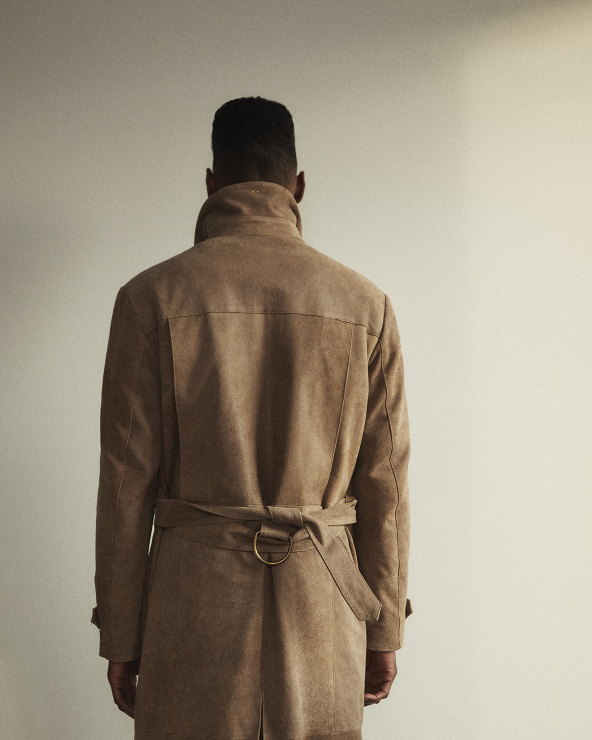 A man wearing a Savas trenchcoat - back view